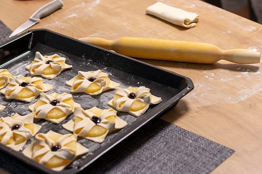 Puff pastry with pineapple wedges wrapped and cherry on top, on the baking tray in the kitchen counter top