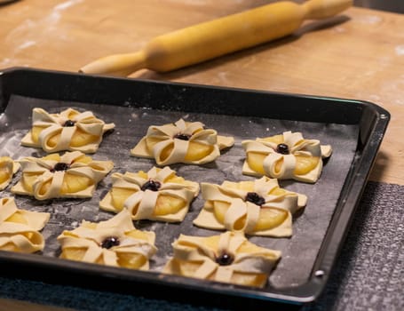 Puff pastry with pineapple wedges wrapped and cherry on top, on the baking tray in the kitchen counter top