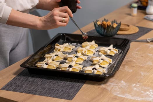 A woman place cherry on the top of the puff pastry with pineapple wedges wrapped.