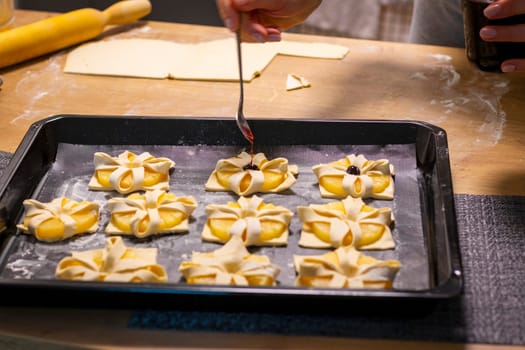 A woman place cherry on the top of the puff pastry with pineapple wedges wrapped.