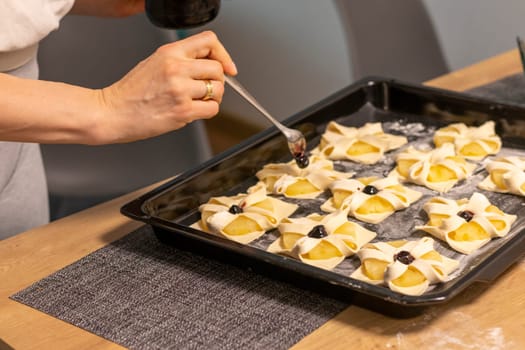A woman place cherry on the top of the puff pastry with pineapple wedges wrapped.