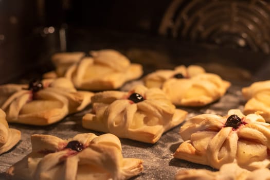 Puff pastry with pineapple wedges wrapped and cherry on top, on the baking tray baking in the oven