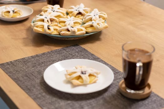 Freshly baked fruit puff pastry on the ceramic plate next to hot cup of coffee
