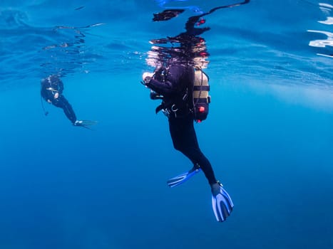 underwater view of unrecognizable scuba diver waiting on the surface of the ocean, concept of active lifestyle and sea adventure, copyspace for text