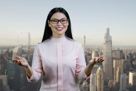 Portrait of a young asian woman is standing outdoors and gesturing. Urban cityscape background.