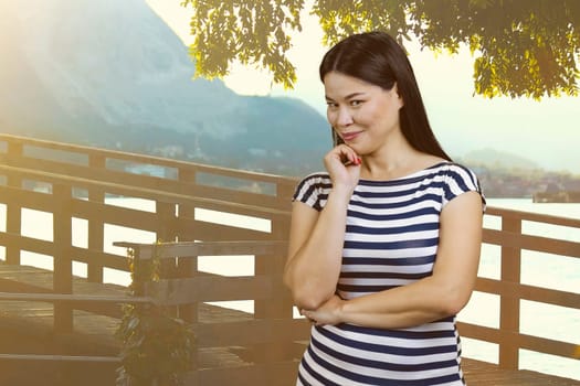 Portrait of attractive brunette asian woman on vacation. Glance at you. Summer resort background.
