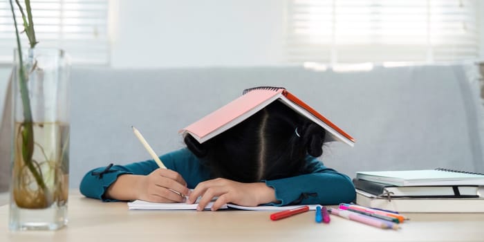 Caught in a moment of stress, a girl rests her head on a notebook, symbolizing the challenges of balancing homework and learning. The image reflects the emotional side of studying.