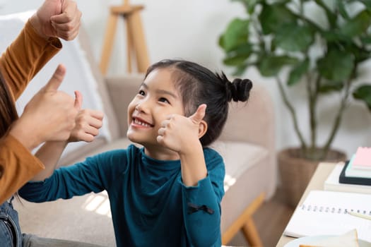 In a moment of joy, a young girl gives a thumbs-up in response to encouragement, highlighting positive reinforcement during her learning process.