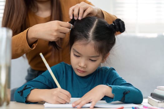 A nurturing figure assists a young girl in her studies, showing the importance of support in education. The moment captures a loving interaction around learning.
