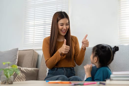 A woman happily encourages a young girl during a learning session, showcasing positive interactions that foster confidence.
