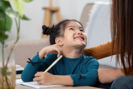 A cheerful girl smiles as she interacts with her mother during a learning session, showcasing the joy of education and bonding.
