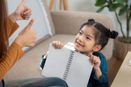 The girl proudly presents her notebook to her mother, receiving encouraging feedback and praise for her work.