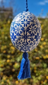 A Ukrainian pysanka hangs gracefully, showcasing intricate blue and white patterns that embody the essence of traditional Easter eggs.