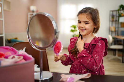 A joyful young girl brushes her hair in front of a mirror, surrounded by colorful accessories in a cozy, well-lit room. Her smile reflects the fun of imaginative play and self-care.