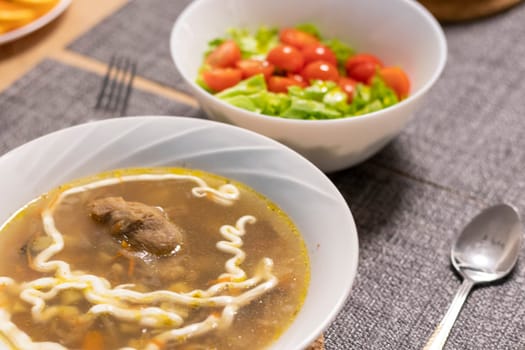 Bawl with cherry tomatoes and lettuce leaves, bawl with soup next to it