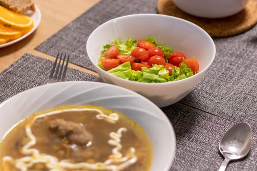 Bawl with cherry tomatoes and lettuce leaves, bawl with soup next to it