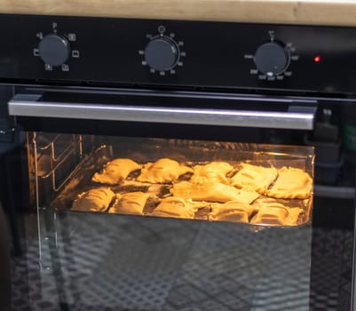 Puff pastries with cottage cheese filling baking in the oven