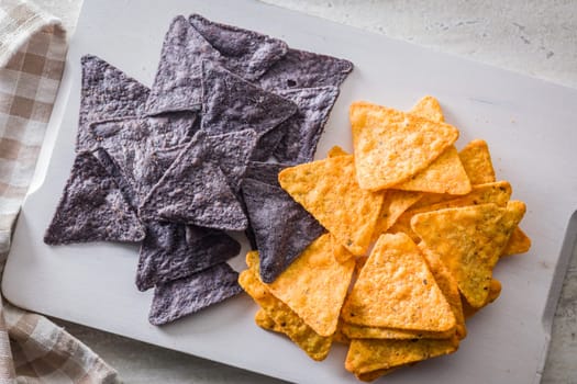 Dark and yellow nachos chips on a kitchen table.