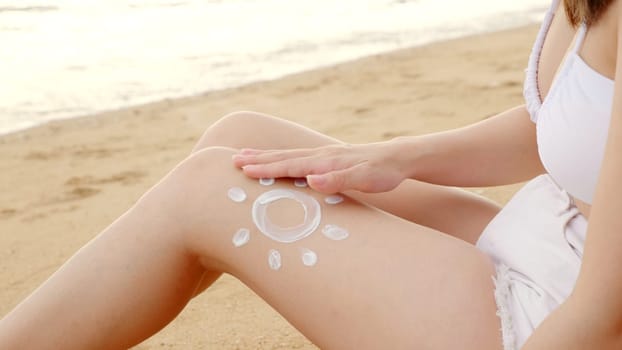 Beautiful Asian woman apply sun protection cream on tanned on leg at tropical beach with white sand, Sun Cream Skincare, Close up female in bikini using sunscreen lotion on back body before sunbathing