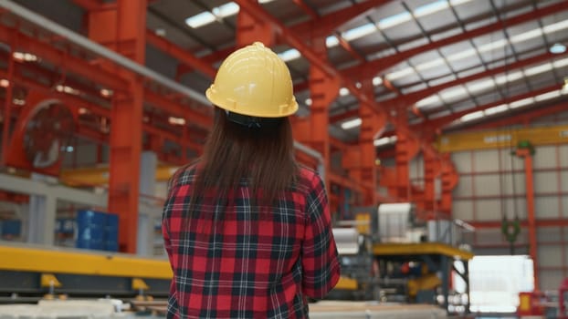 Back professional heavy Industry engineer woman worker wearing safety helmet using clipboard to checking she work production in factory industry manufacture
