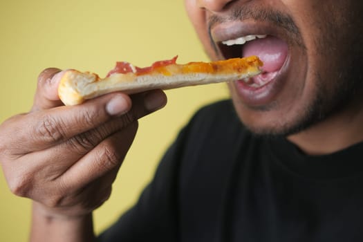 Man takes a bite of pizza slice topped with cheese and meat.