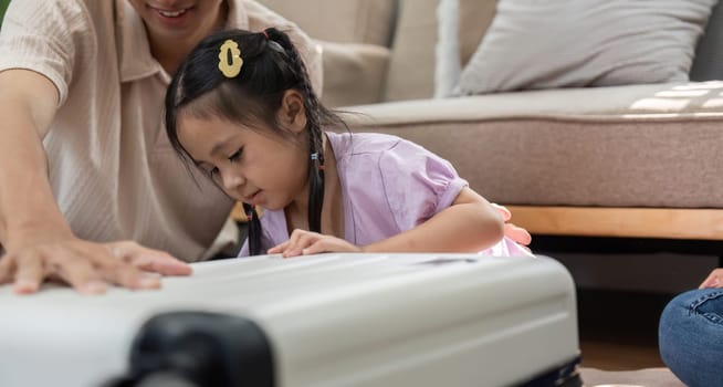 In a friendly environment, an engaged mother and father encourage their daughter as she examines a suitcase, embodying fun and growth through play and imagination.