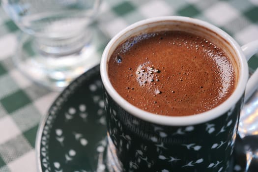 Enjoying turkish coffee in a cozy cafe setting with checkered tablecloth.