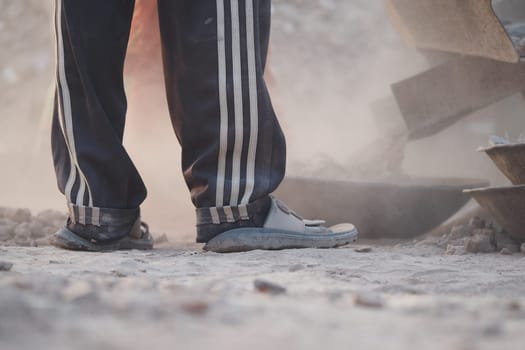 Construction worker stands amid dust and debris, focusing on tasks.