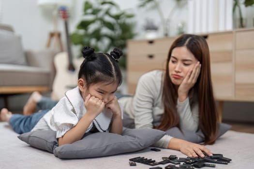 A mother comforts her daughter as they struggle with a game, illustrating the challenges of learning and patience in family interactions.