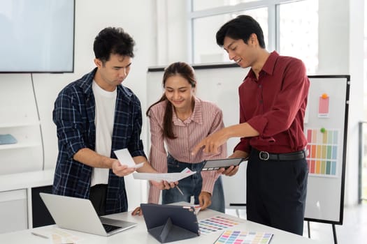 In a modern office, three professionals analyze design papers and digital tools, fostering a collaborative environment aimed at creating innovative solutions together.
