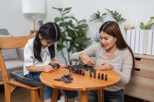 The excitement builds as a mother and daughter strategize during their domino game, highlighting the importance of family relationships in playful scenarios.
