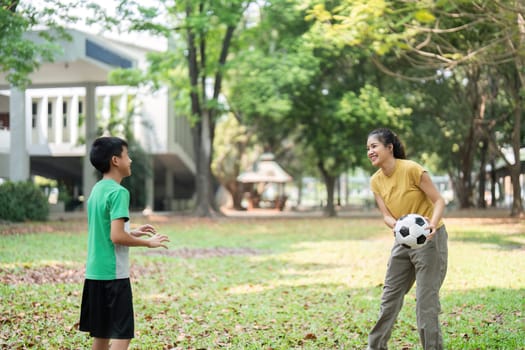 In a lively park, a girl holds a soccer ball while interacting with her friend, encouraging each other during their playtime filled with initiative and fun.