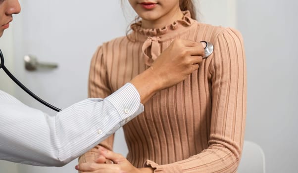 A doctor is examining a patient, using a stethoscope to check her heart rate and overall health in a caring consultation setting.