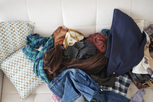 Various clothing items are scattered on a couch in a casual setting.