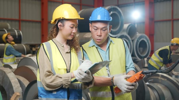 Supervisor senior man training controlling overhead crane with remote new worker in manufacturing, Engineering team use remote control panel for lifting down power trolley crane in factory warehouse