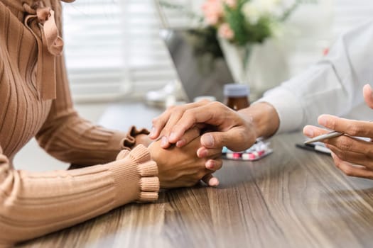 A healthcare provider offers emotional support by holding the patient's hand, emphasizing the importance of care in patient-provider relationships.