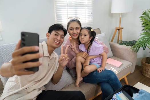 A family poses for a selfie, displaying laughter and love in their home, capturing memories before a fun trip.