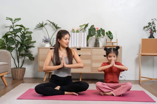 In a serene home setting, a mother and daughter engage in yoga, harmonizing their breath and fostering a deeper bond through shared mindfulness and playful interaction.