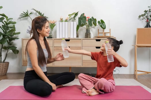 The interaction highlights the joy of sharing as a mother and daughter celebrate their yoga practice by exchanging water bottles, reinforcing their close relationship.