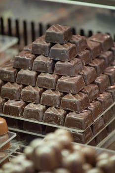 A pyramid of assorted chocolate treats fills a display case in a shop.