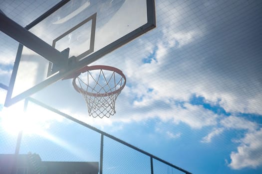 Players enjoy shooting hoops while basking in the sunny afternoon light.