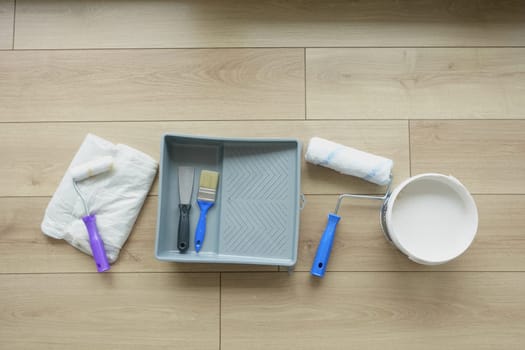 Set of painting tools neatly arranged on a wooden floor ready for use.
