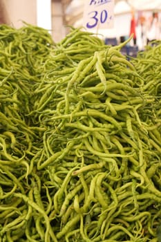 Vibrant green chilies are piled high at a busy market stall.