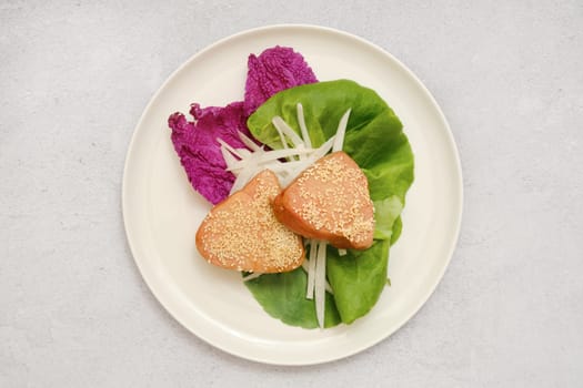 Two pieces of tuna steaks on a bed of fresh greens, including crisp lettuce and purple cabbage.