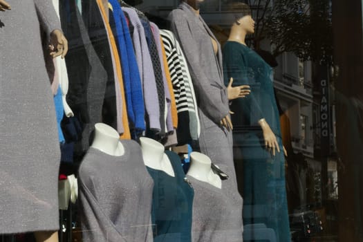 Elegant dresses and stylish clothing are showcased in a boutique window.
