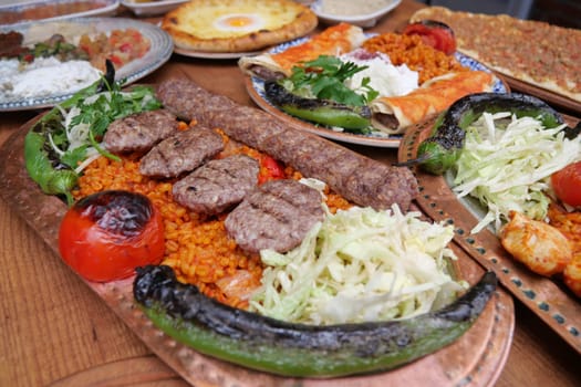 Grilled meats topped with fresh vegetables and flavorful rice are served.