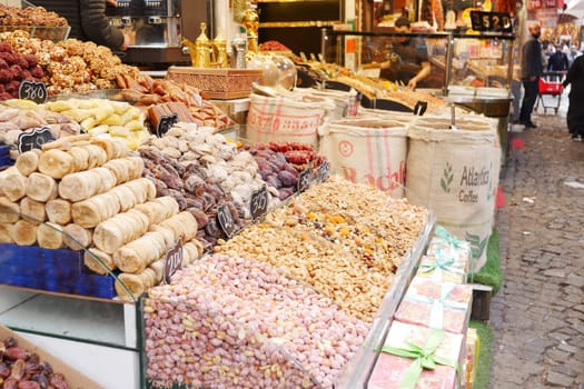 Stalls filled with various nuts and dried fruits attract shoppers in a market.