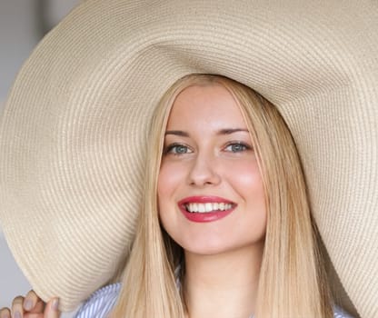 Woman, fashion and summer country charm, blonde beauty and elegance in wide brimmed beach hat. Feminine allure, timeless style and graceful glow. Smile, straw hat and blue striped blouse, natural lighting and effortless charm, fashion look idea