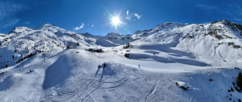 A breathtaking aerial view of a beautiful winter landscape with snow-covered alpine mountains, sunny skies, and scenic slopes perfect for skiing, snowboarding, hiking, and outdoor adventures