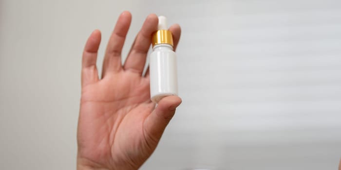 In a moment of focus, a hand presents a beauty serum dropper, underlining the importance of skincare in enhancing overall beauty and wellness.